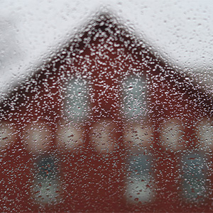 Photo of a rainy window with a red house in background